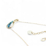 A brass infinity-shaped pendant necklace with blue faceted apatite and opal gemstones on the inside, attached to a gold-filled chain with an adjustable clasp.