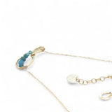 A brass infinity-shaped pendant necklace with blue faceted apatite and opal gemstones on the inside, attached to a gold-filled chain with an adjustable clasp.