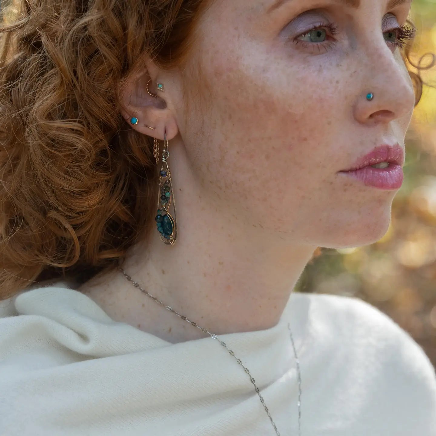 Apatite gemstones accented with blue quartz, chrysocolla, crystal, and bright apatite gemstones wrapped in bronze and gold filled wire inside darkened sterling silver long drop earrings