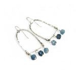 A pair of sterling silver arch earrings with faceted aquamarine gemstones attached to the bottom