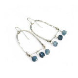 A pair of sterling silver arch earrings with faceted aquamarine gemstones attached to the bottom