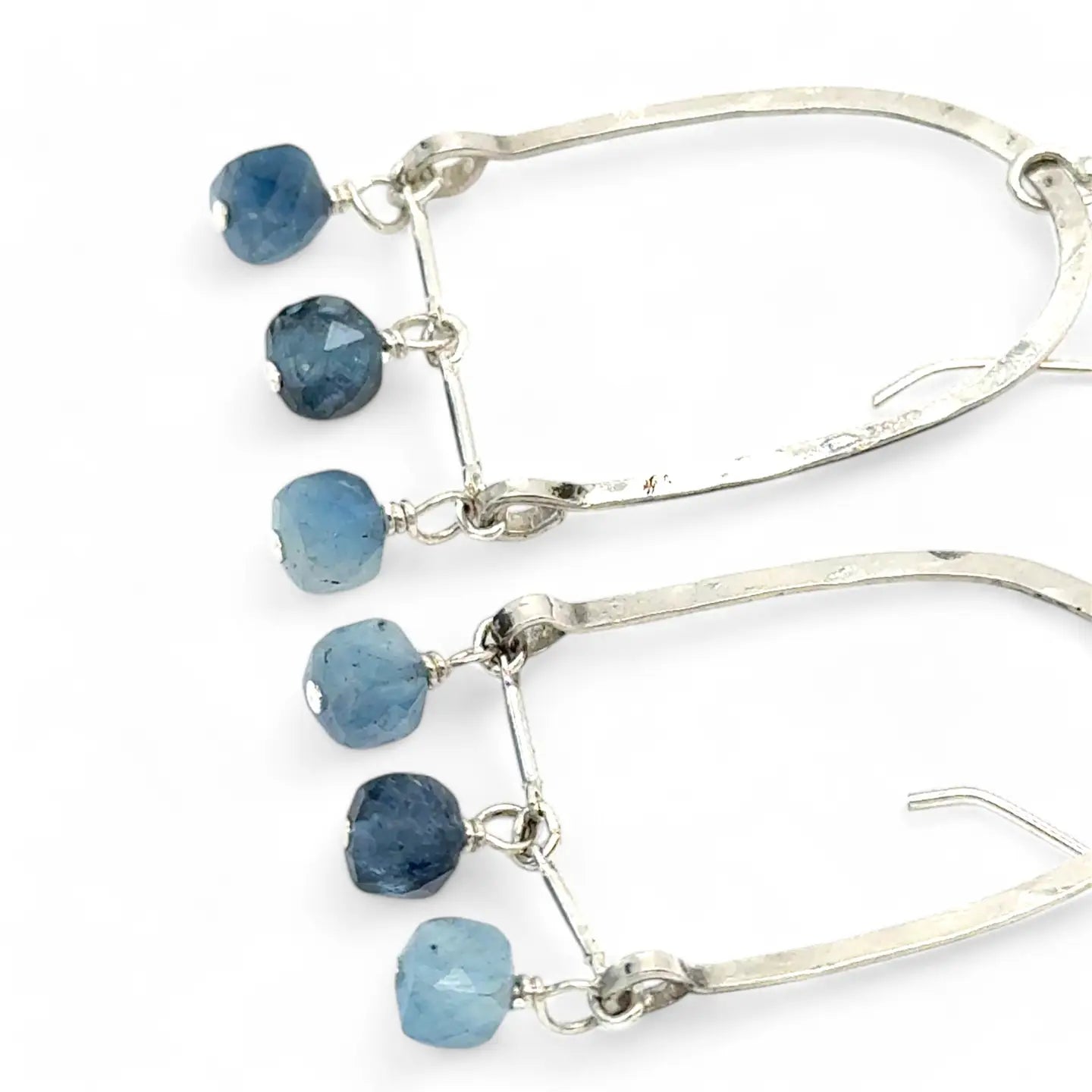 A pair of sterling silver arch earrings with faceted aquamarine gemstones attached to the bottom