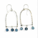 A pair of sterling silver arch earrings with faceted aquamarine gemstones attached to the bottom