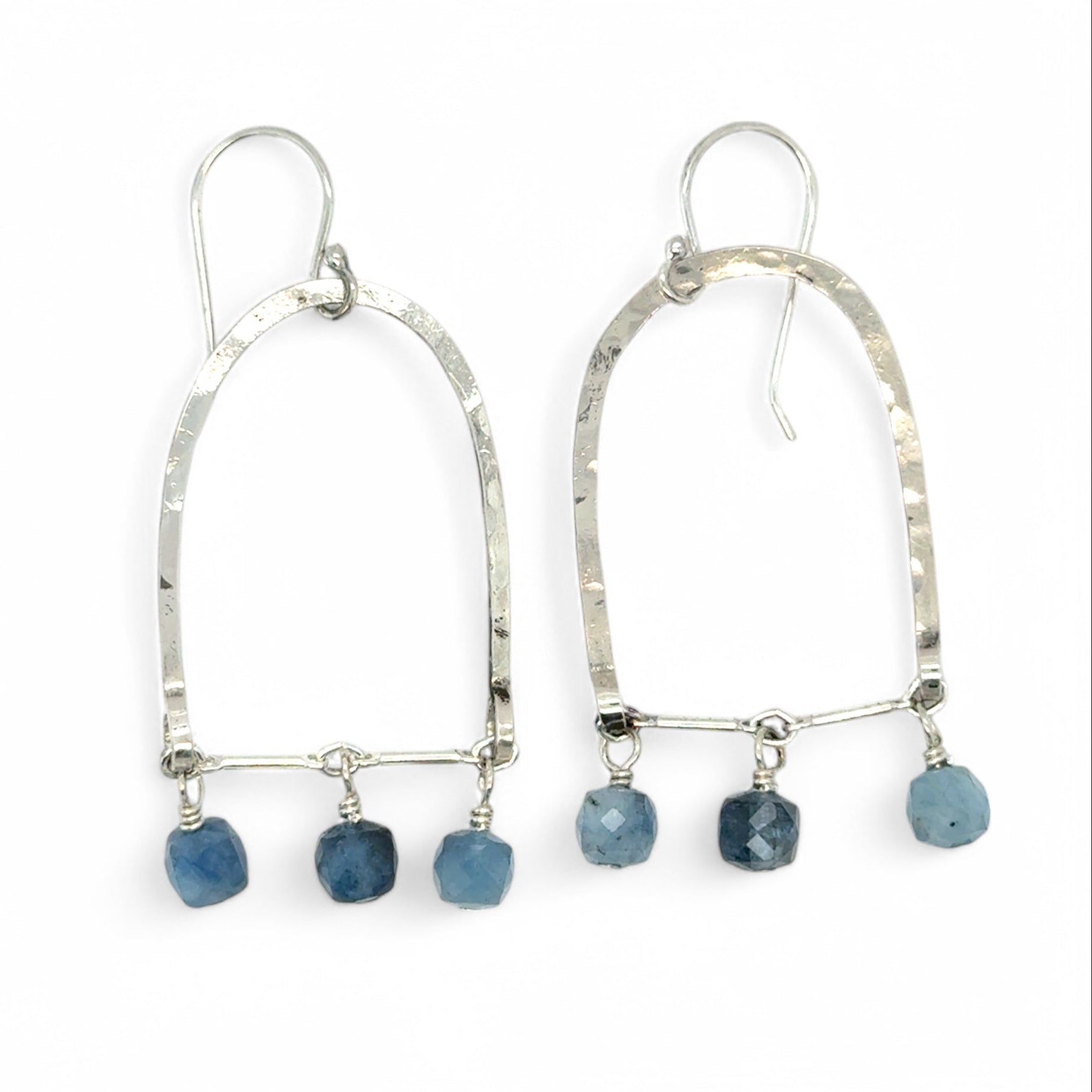 A pair of sterling silver arch earrings with faceted aquamarine gemstones attached to the bottom