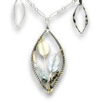 Charm necklace with bronze, sterling silver, and darkened sterling braided petal shapes, accompanied by opal, a carved aquamarine flower, apatite, and crystal gemstones