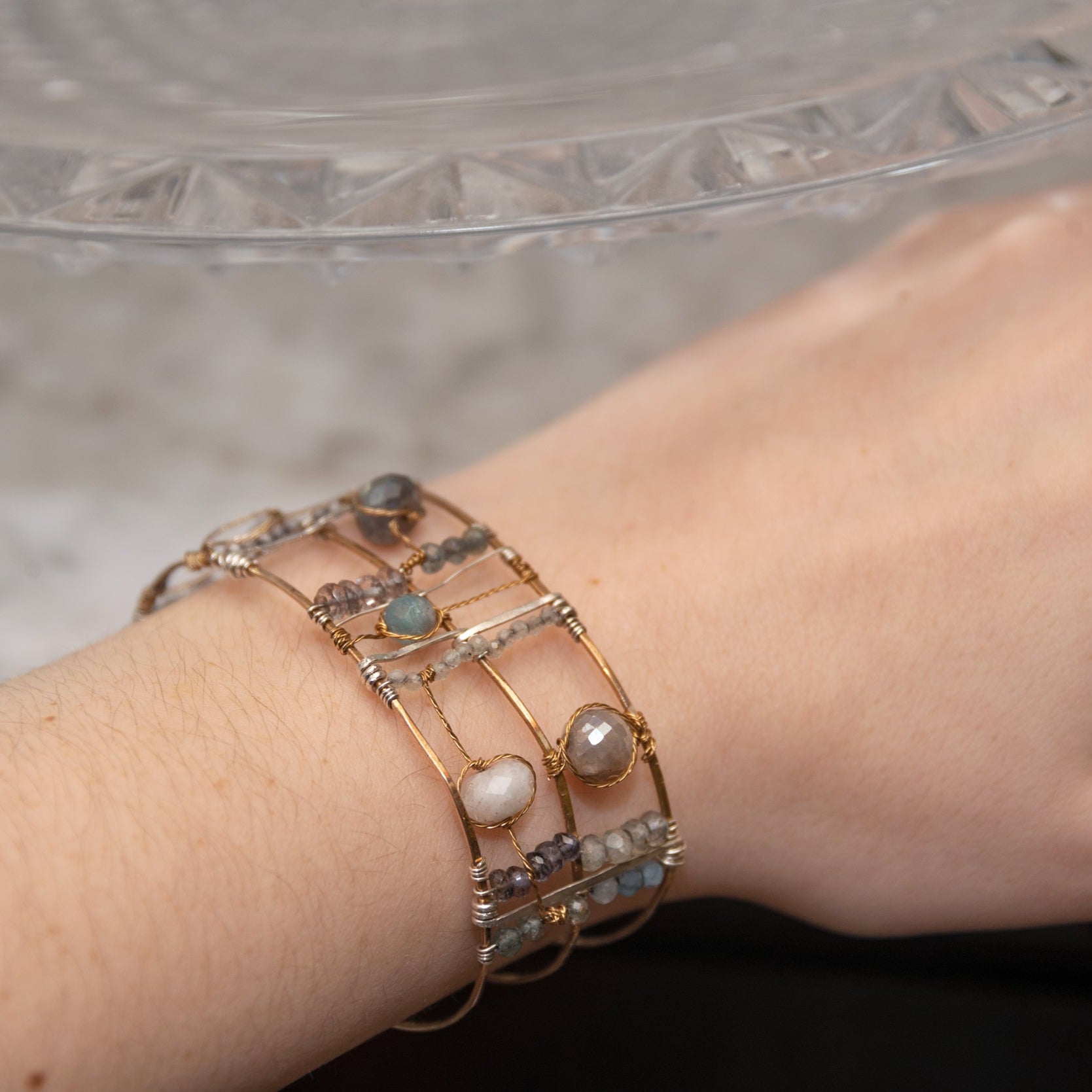 Wide bronze double cuff with sterling silver hammered bars decorated in a plaid pattern with aquamarine, moonstone, labradorite, apatite, and iolite gemstones