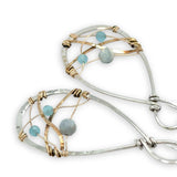 Aquamarine faceted gemstones weaved in gold filled wire along side brass hammered wire on a handmade sterling silver infinity shaped earrings