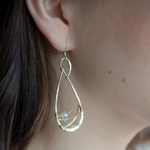 Aquamarine faceted gemstones weaved in gold filled wire along side brass hammered wire on a handmade sterling silver infinity shaped earrings