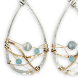 Aquamarine faceted gemstones weaved in gold filled wire along side brass hammered wire on a handmade sterling silver infinity shaped earrings