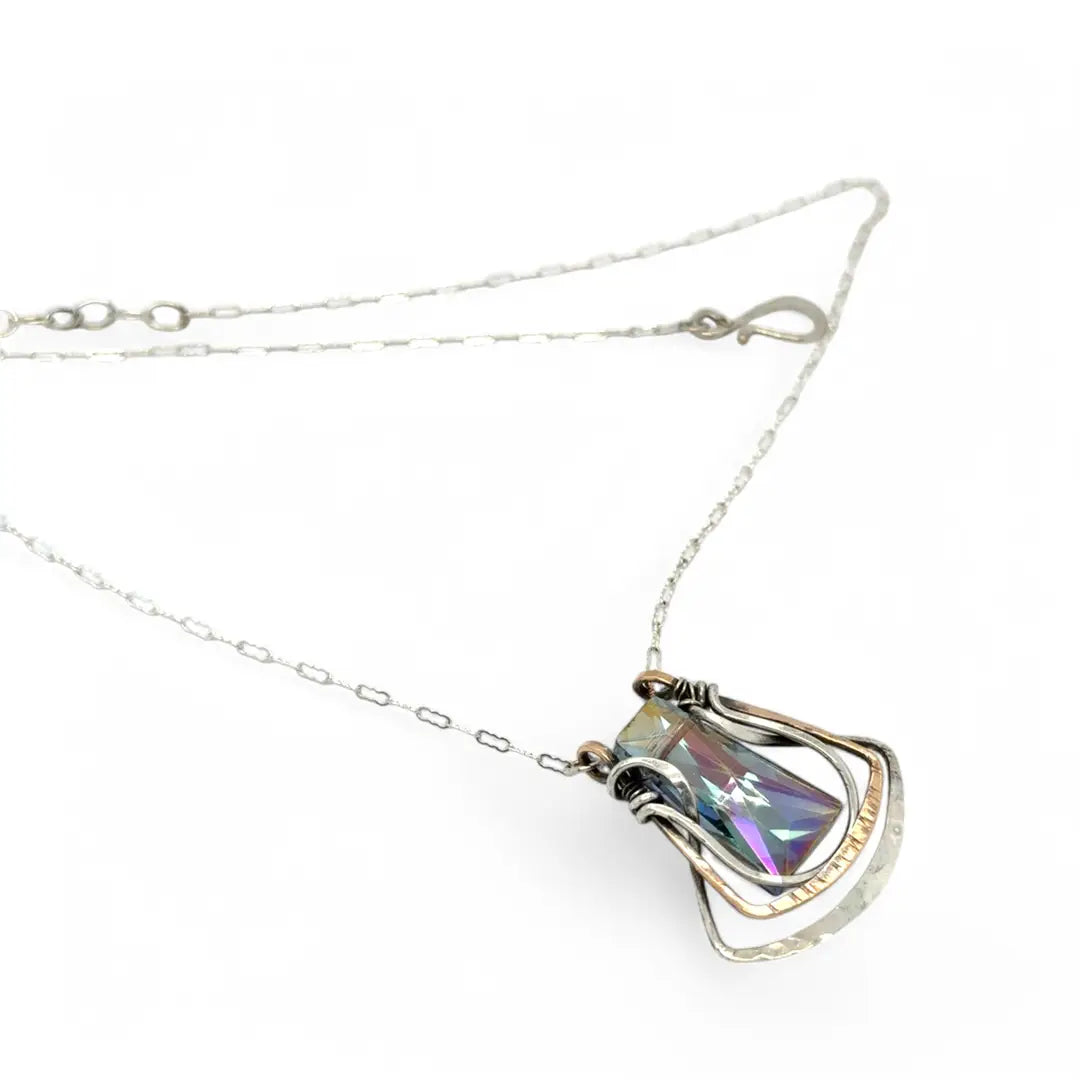 A blue/purple rectangular crystal is held in layers of sterling silver and bronze hammered wire pendant on sterling silver delicate chain necklace
