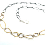 An artisanal chain necklace with a combination of handmade hammered brass links and open diamond cut oxidized sterling links 