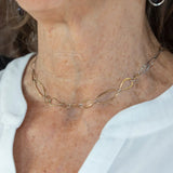 An artisanal chain necklace with a combination of handmade hammered brass links and open diamond cut oxidized sterling links 