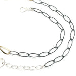 An artisanal chain necklace with a combination of handmade hammered brass links and open diamond cut oxidized sterling links 