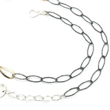 An artisanal chain necklace with a combination of handmade hammered brass links and open diamond cut oxidized sterling links 