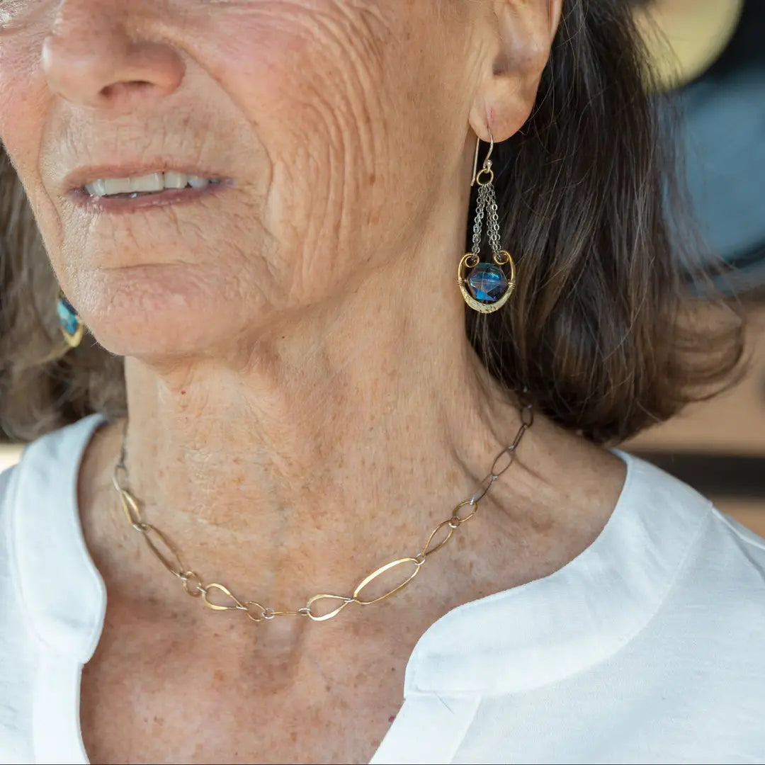 An artisanal chain necklace with a combination of handmade hammered brass links and open diamond cut oxidized sterling links 
