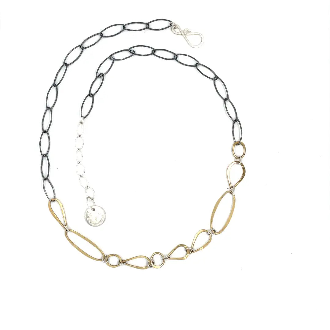 An artisanal chain necklace with a combination of handmade hammered brass links and open diamond cut oxidized sterling links 