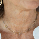 An artisanal chain necklace with a combination of handmade hammered brass links and open diamond cut oxidized sterling links 