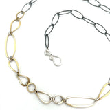 An artisanal chain necklace with a combination of handmade hammered brass links and open diamond cut oxidized sterling links 