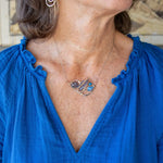 Darkened sterling silver boomerang shaped pendant necklace with waves of hammered bronze, sterling silver, and gold filled wire holding smooth labradorite, blue jade, blue crystal, and a purple fresh water stick pearl in place