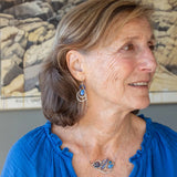 Darkened sterling silver boomerang shaped pendant necklace with waves of hammered bronze, sterling silver, and gold filled wire holding smooth labradorite, blue jade, blue crystal, and a purple fresh water stick pearl in place