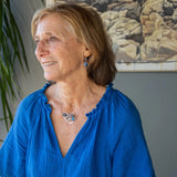 Darkened sterling silver boomerang shaped pendant necklace with waves of hammered bronze, sterling silver, and gold filled wire holding smooth labradorite, blue jade, blue crystal, and a purple fresh water stick pearl in place