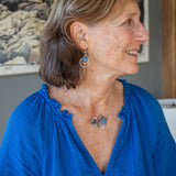 Darkened sterling silver boomerang shaped pendant necklace with waves of hammered bronze, sterling silver, and gold filled wire holding smooth labradorite, blue jade, blue crystal, and a purple fresh water stick pearl in place