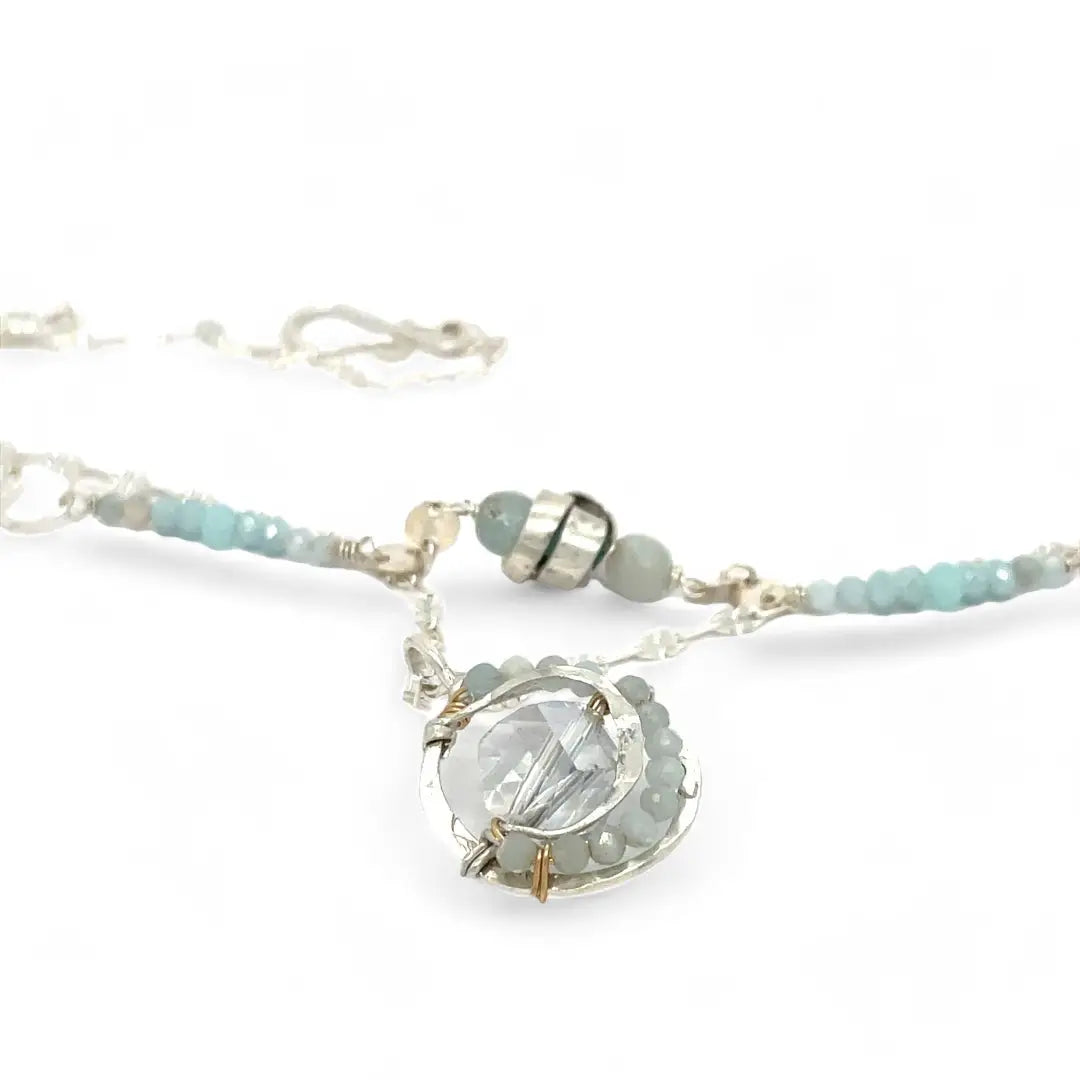 A sterling silver double strand necklace with chain links, twisted knot, amazonite, and aquamarine gemstones, featuring a blue rhomboid crystal pendant.