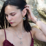 A sterling silver double strand necklace with chain links, twisted knot, amazonite, and aquamarine gemstones, featuring a blue rhomboid crystal pendant.