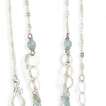 A sterling silver double strand necklace with chain links, twisted knot, amazonite, and aquamarine gemstones, featuring a blue rhomboid crystal pendant.