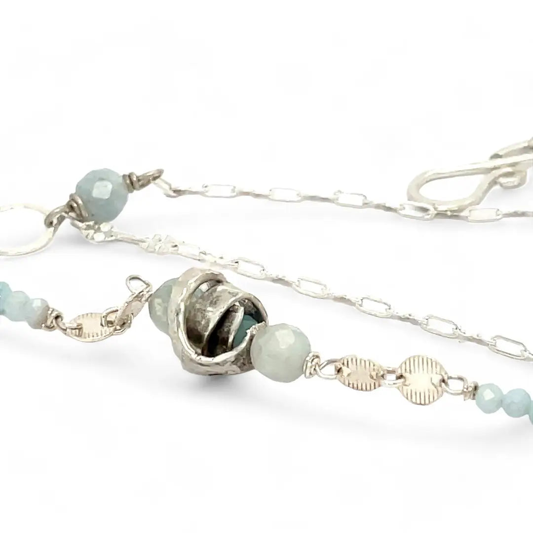 A sterling silver double strand necklace with chain links, twisted knot, amazonite, and aquamarine gemstones, featuring a blue rhomboid crystal pendant.