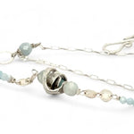 A sterling silver double strand necklace with chain links, twisted knot, amazonite, and aquamarine gemstones, featuring a blue rhomboid crystal pendant.