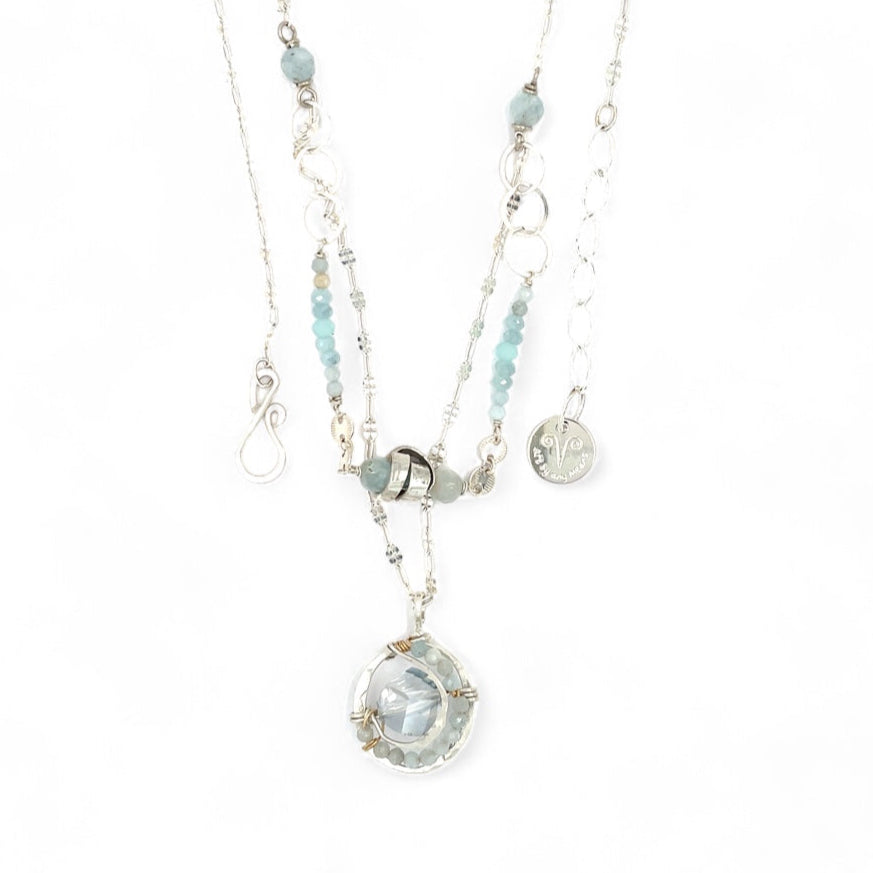 A sterling silver double strand necklace with chain links, twisted knot, amazonite, and aquamarine gemstones, featuring a blue rhomboid crystal pendant.