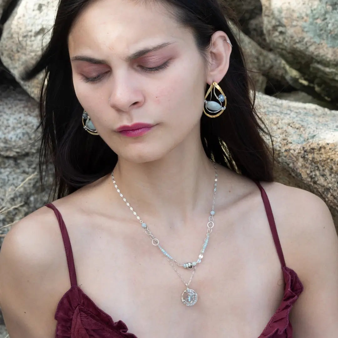 A sterling silver double strand necklace with chain links, twisted knot, amazonite, and aquamarine gemstones, featuring a blue rhomboid crystal pendant.