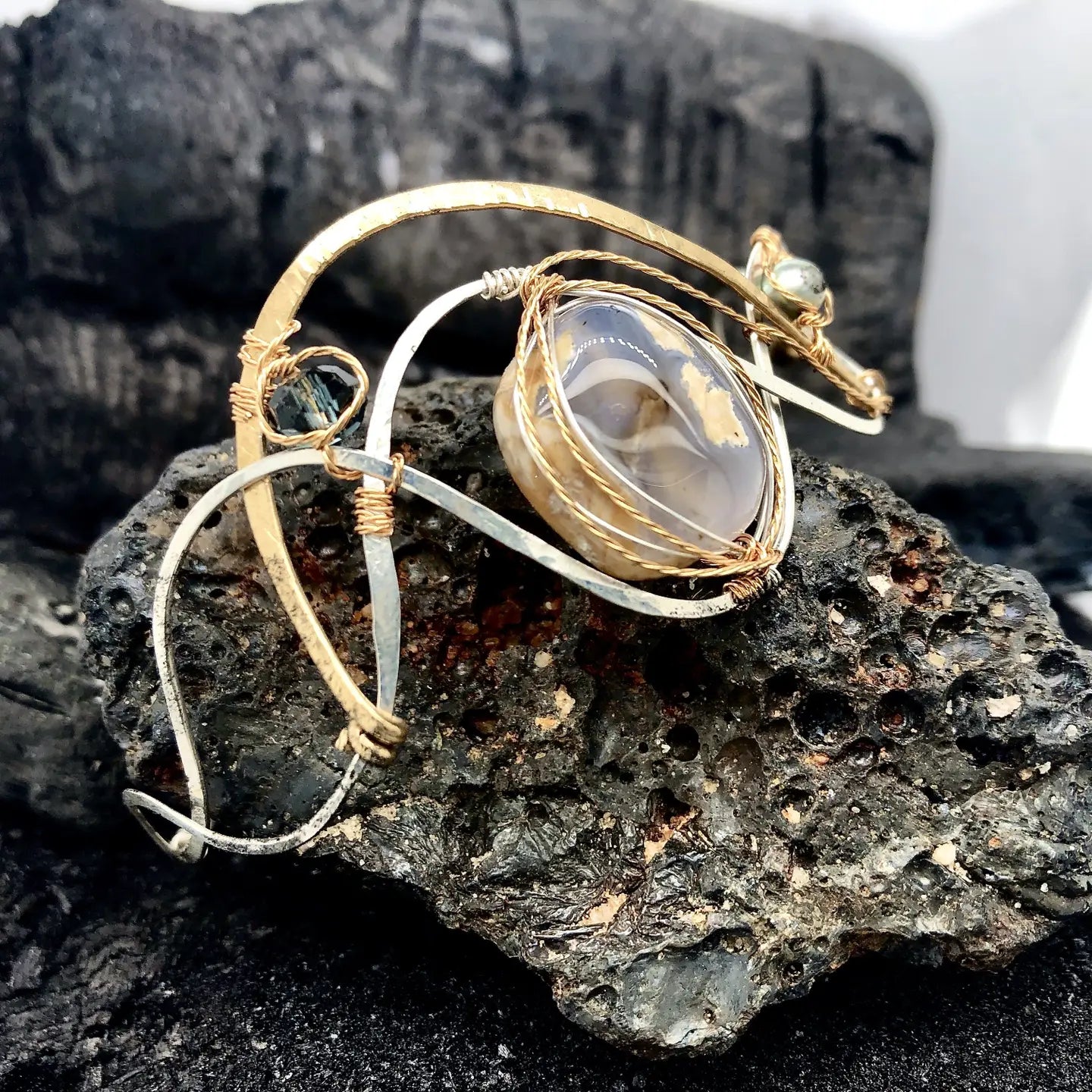 light purple chalcedony smooth nugget surrounded by layers of hammered sterling silver and brass wires to form a statement bracelet accented with fresh water pearl and crystal