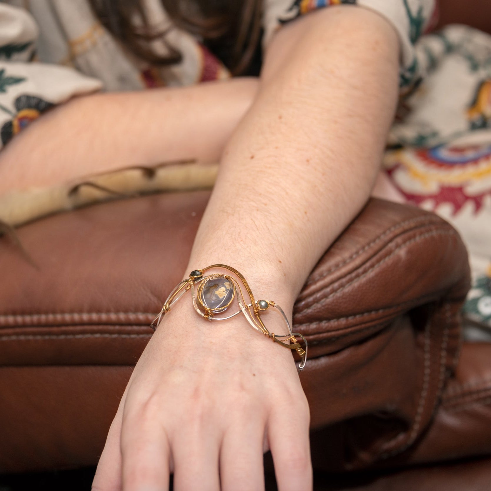 light purple chalcedony smooth nugget surrounded by layers of hammered sterling silver and brass wires to form a statement bracelet accented with fresh water pearl and crystal