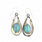 A pair of handcrafted oxidized sterling silver drop earrings with hammered brass, aqua blue quartz crystal centers and gold-filled details