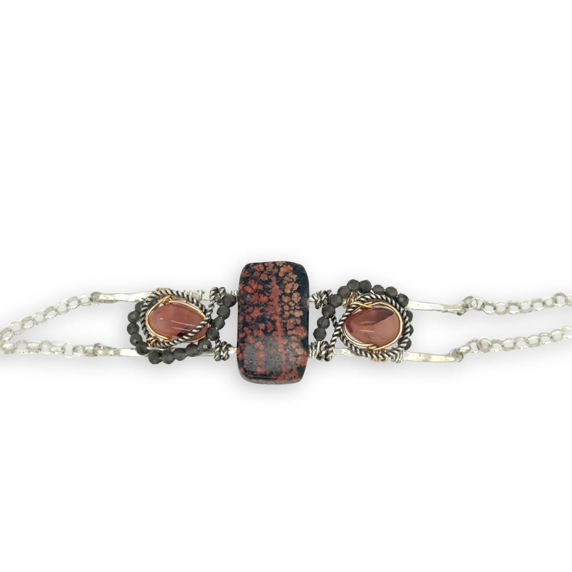 Red fossil jasper, rhodochrosite, and green obsidian gemstones fill the sterling silver bar bracelet with rolo chain backing