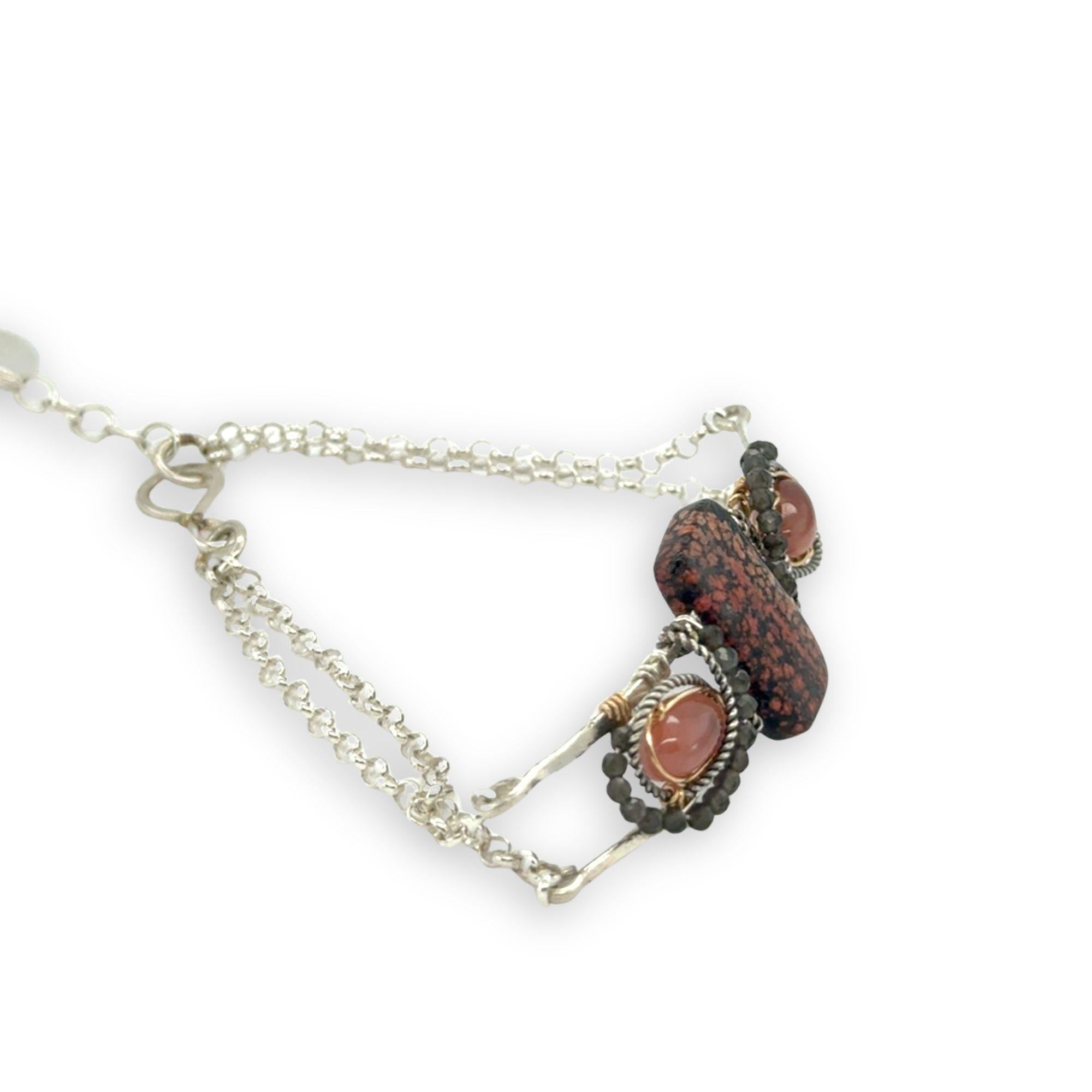 Red fossil jasper, rhodochrosite, and green obsidian gemstones fill the sterling silver bar bracelet with rolo chain backing