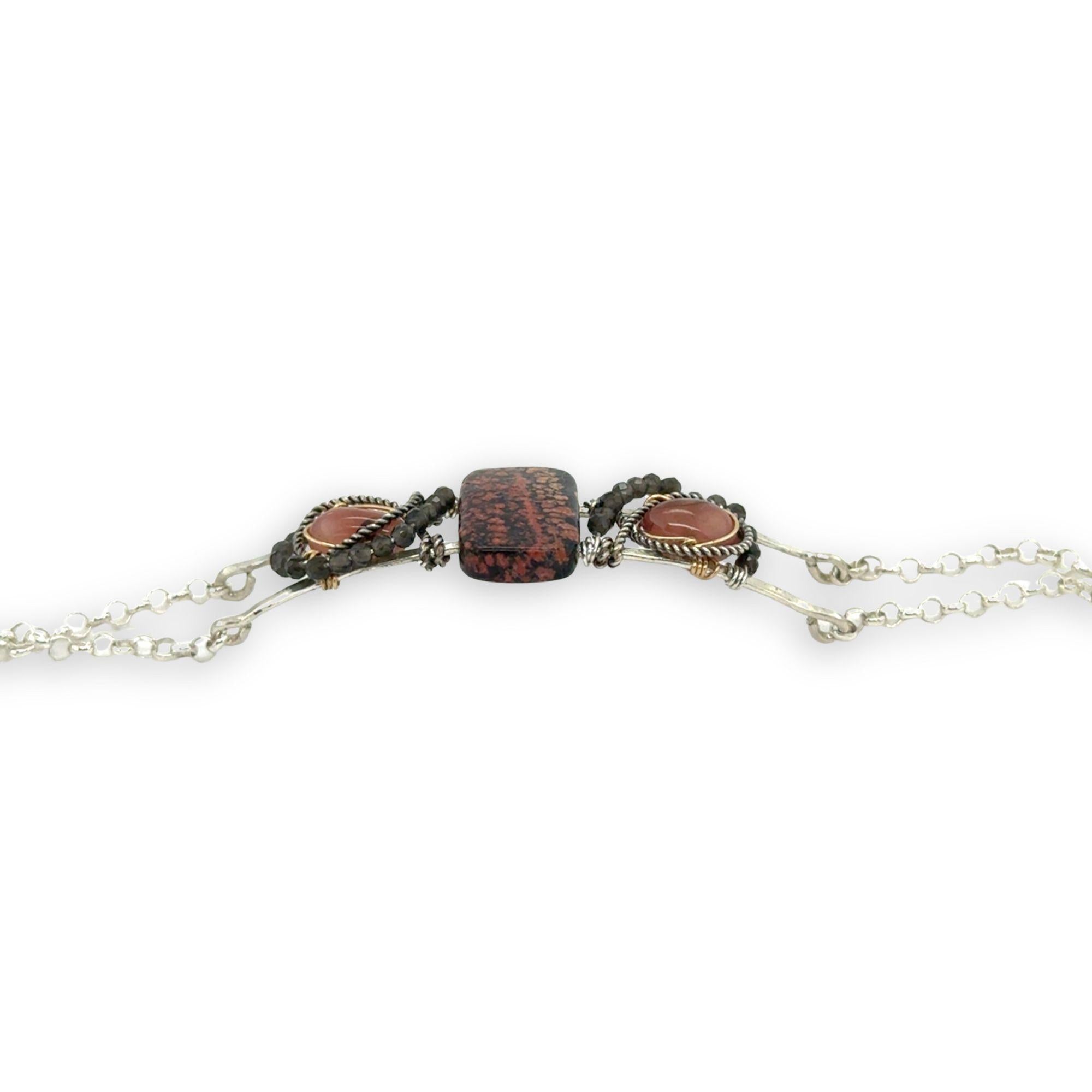 Red fossil jasper, rhodochrosite, and green obsidian gemstones fill the sterling silver bar bracelet with rolo chain backing