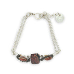 Red fossil jasper, rhodochrosite, and green obsidian gemstones fill the sterling silver bar bracelet with rolo chain backing