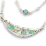 Double layered necklace with the first layer being sterling bar chain with blue opals, the second layer with a sterling moon shaped pendant filled with apatite and bold opal gemstones in 14k gold filled swirls