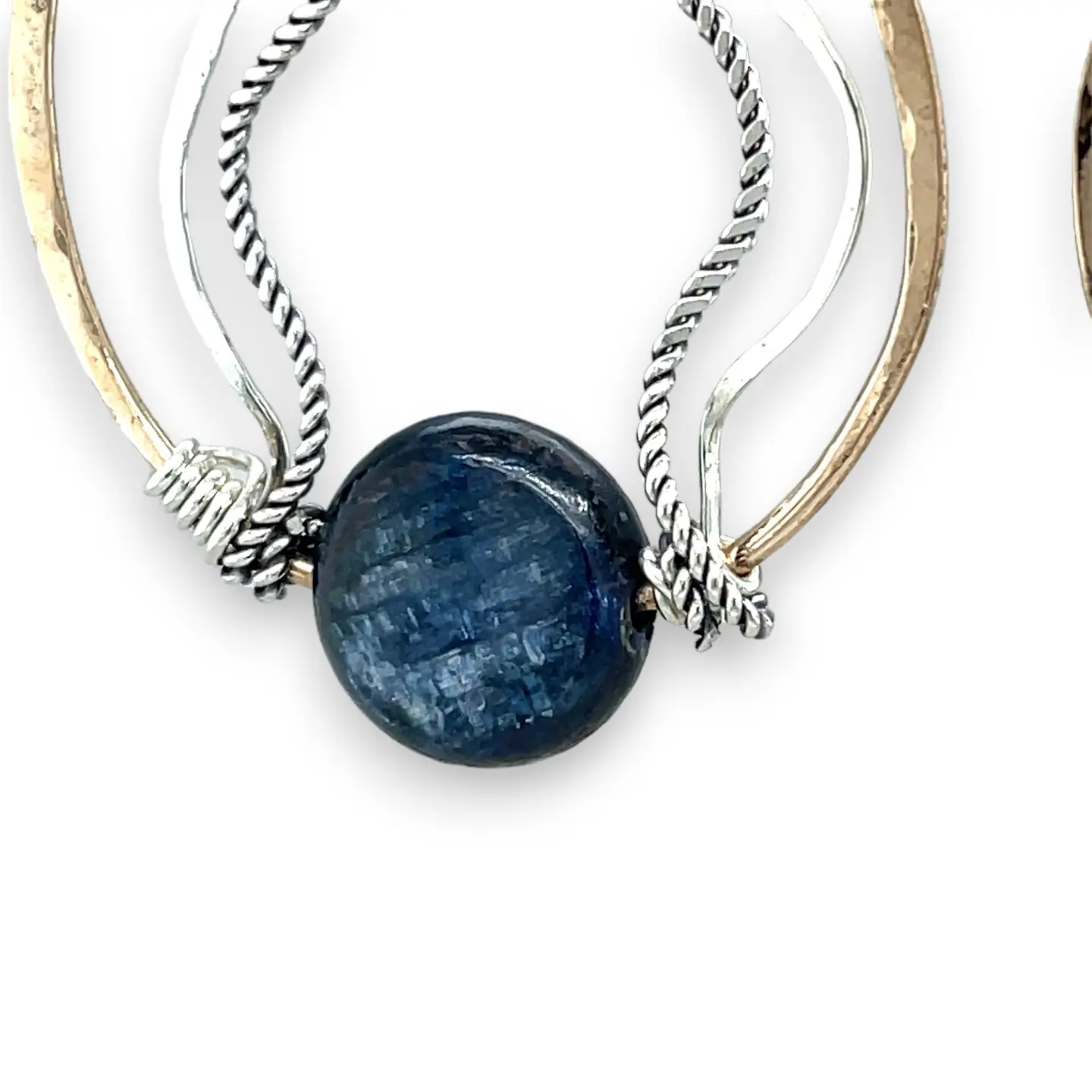 A bronze hoop earring with sparkly sterling silver and oxidized twisted sterling silver swishes holding a blue kyanite stone.