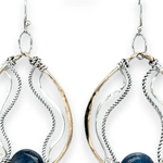 A bronze hoop earring with sparkly sterling silver and oxidized twisted sterling silver swishes holding a blue kyanite stone.