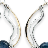 A bronze hoop earring with sparkly sterling silver and oxidized twisted sterling silver swishes holding a blue kyanite stone.