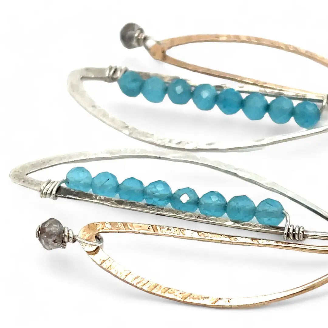 A pair of dangling earrings with sterling silver and bronze semi-circle elements, accented with tiny faceted aqua cat's eye gemstones and labradorite dangles