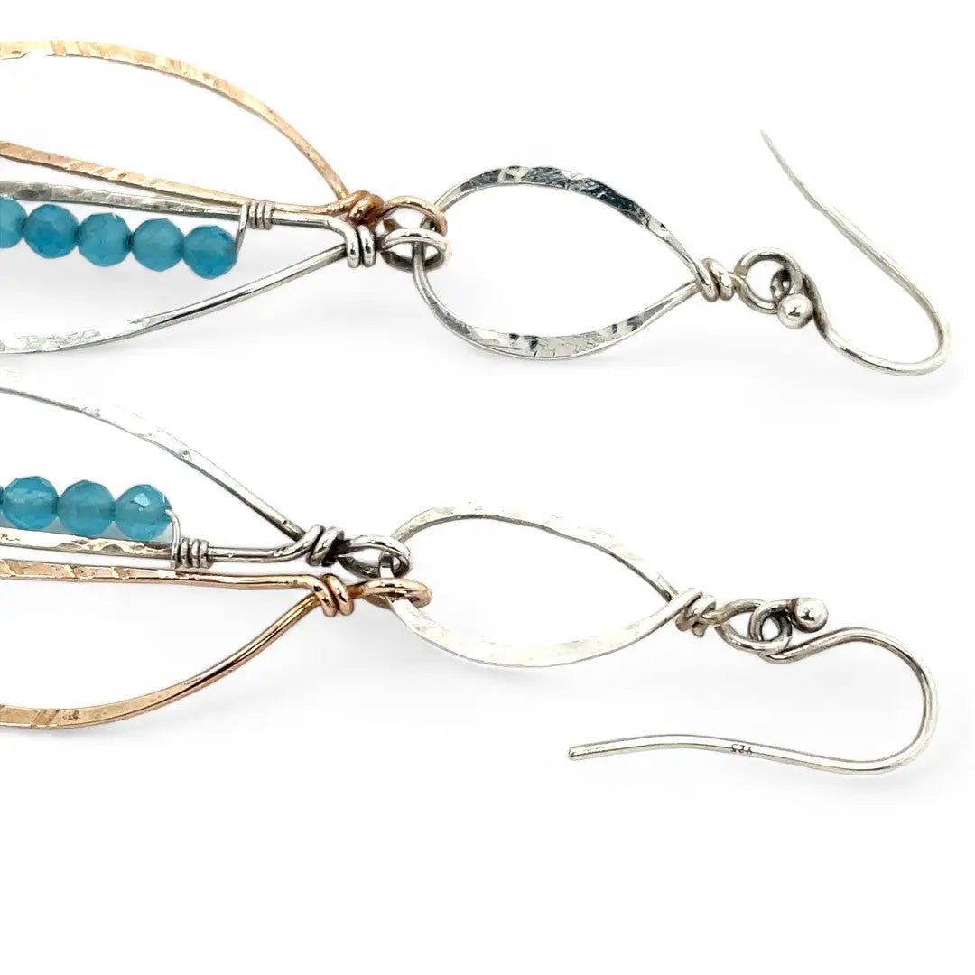 A pair of dangling earrings with sterling silver and bronze semi-circle elements, accented with tiny faceted aqua cat's eye gemstones and labradorite dangles