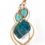 A pair of gold-colored brass earrings with a double drop design, featuring blue green chrysocolla marquise gemstones and chalcedony wrapped in gold filled wire