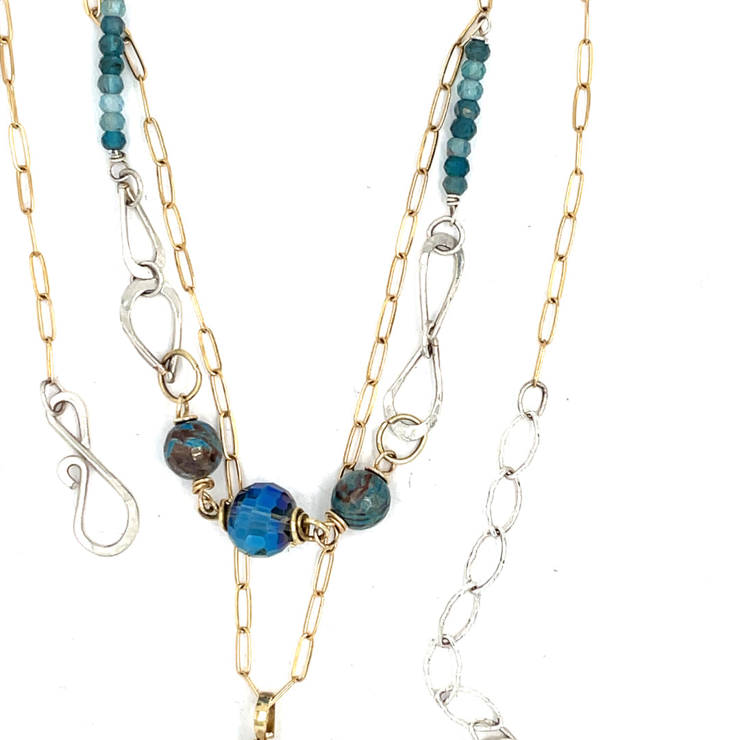 A sterling silver handmade chain link necklace with a brass charm holding an aquamarine coin, with faceted chrysocolla, apatite and blue disco ball crystal on gold filled delicate chain