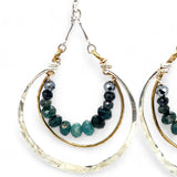 Blue tourmaline gemstones line the inside of a brass ring with hammered sterling silver outside ring, hanging from a sterling silver bar chain