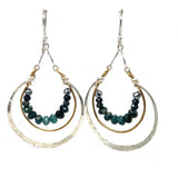 Blue tourmaline gemstones line the inside of a brass ring with hammered sterling silver outside ring, hanging from a sterling silver bar chain